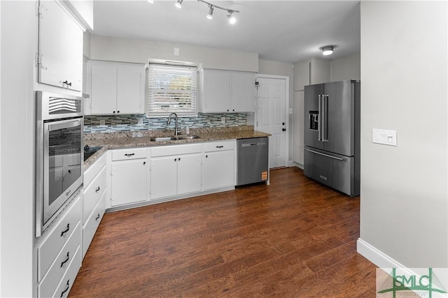 kitchen featuring dark wood finished floors, a sink, white cabinets, appliances with stainless steel finishes, and backsplash