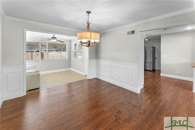 unfurnished dining area featuring visible vents, crown molding, a wainscoted wall, and wood finished floors