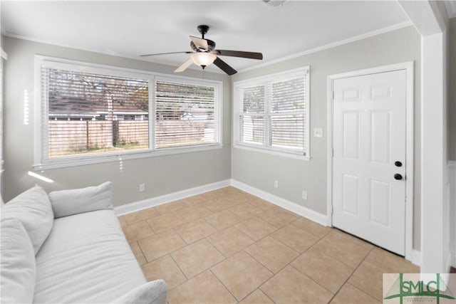 living area with light tile patterned floors, a ceiling fan, baseboards, and ornamental molding