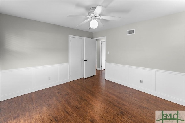 unfurnished room featuring wainscoting, wood finished floors, visible vents, and ceiling fan