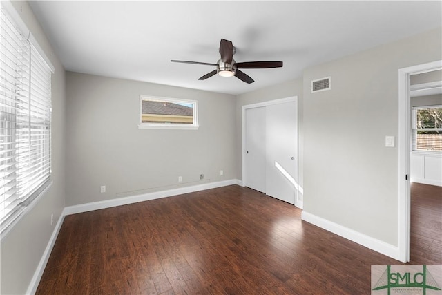 unfurnished bedroom featuring visible vents, baseboards, a closet, and wood finished floors