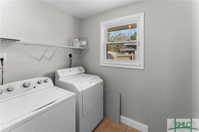 clothes washing area with light tile patterned floors, laundry area, baseboards, and separate washer and dryer