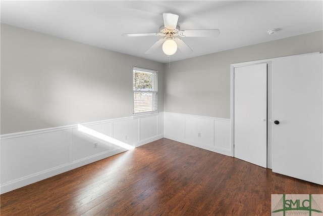 spare room with a wainscoted wall, wood finished floors, and a ceiling fan