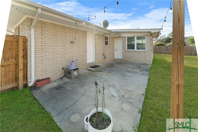 back of house featuring a patio, fence, a lawn, and brick siding