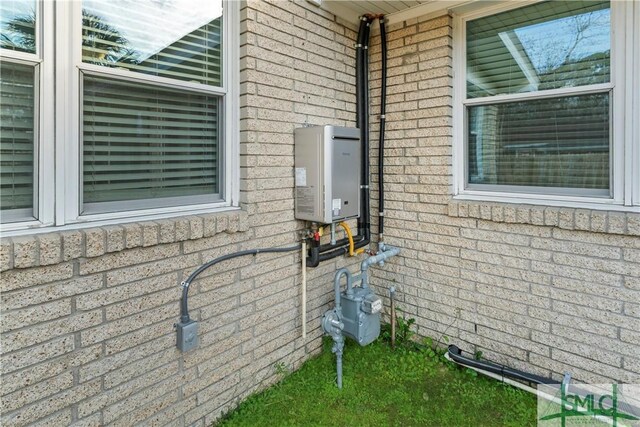 exterior details featuring brick siding, water heater, and gas meter