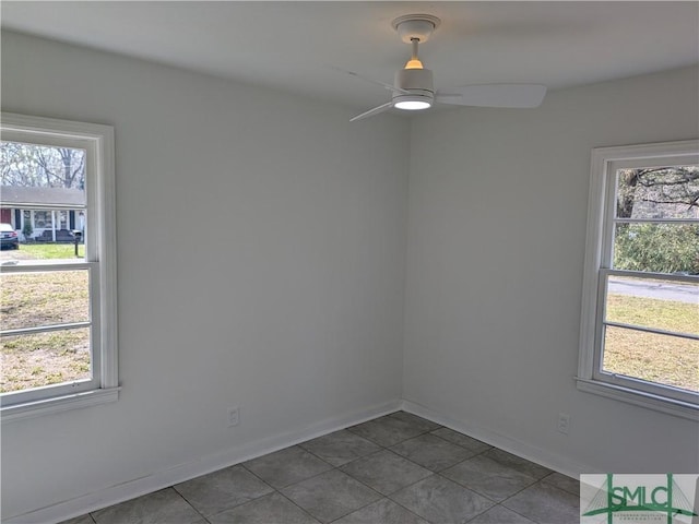 empty room with baseboards, dark tile patterned flooring, and ceiling fan