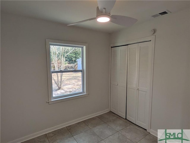 unfurnished bedroom featuring light tile patterned floors, a ceiling fan, baseboards, visible vents, and a closet