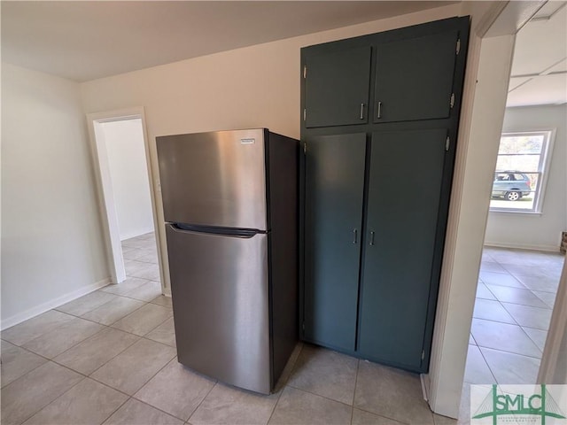 kitchen with light tile patterned flooring, baseboards, and freestanding refrigerator