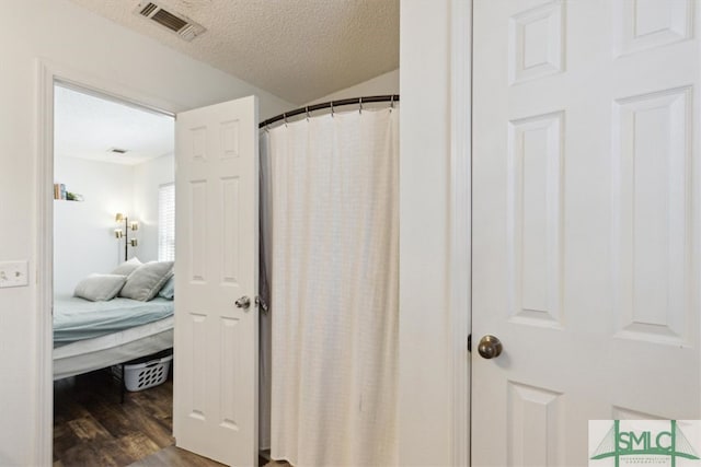 full bath with ensuite bath, wood finished floors, visible vents, and a textured ceiling