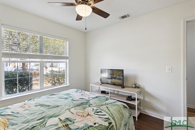 bedroom with visible vents, a ceiling fan, a textured ceiling, baseboards, and dark wood-style flooring