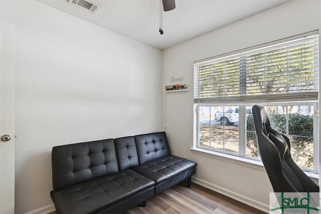 sitting room featuring visible vents, baseboards, wood finished floors, a textured ceiling, and a ceiling fan