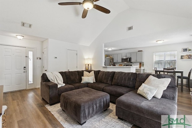 living area with visible vents, high vaulted ceiling, a ceiling fan, and wood finished floors