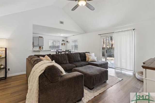 living area with visible vents, baseboards, wood finished floors, high vaulted ceiling, and a ceiling fan