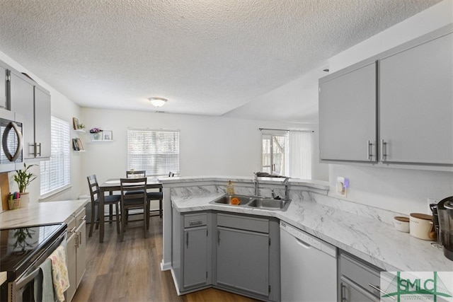 kitchen featuring gray cabinetry, light countertops, appliances with stainless steel finishes, a peninsula, and a sink