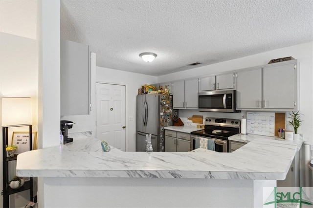 kitchen featuring visible vents, a peninsula, gray cabinetry, appliances with stainless steel finishes, and a textured ceiling