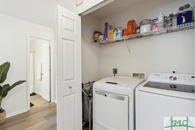 clothes washing area with laundry area, washing machine and dryer, and wood finished floors