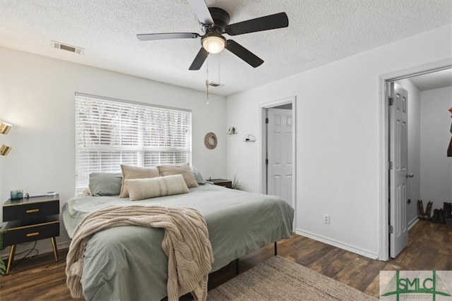 bedroom featuring visible vents, a textured ceiling, wood finished floors, baseboards, and ceiling fan