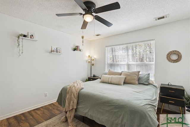 bedroom with visible vents, baseboards, a textured ceiling, and wood finished floors