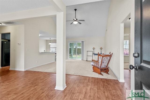 foyer entrance with visible vents, baseboards, ceiling fan, light wood-style flooring, and high vaulted ceiling