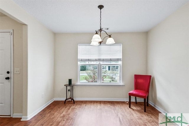 living area featuring visible vents, a notable chandelier, wood finished floors, and baseboards