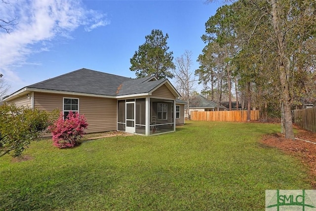 rear view of property featuring a lawn, fence, and a sunroom