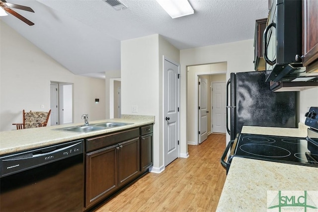 kitchen featuring visible vents, light wood-style flooring, a sink, black appliances, and light countertops