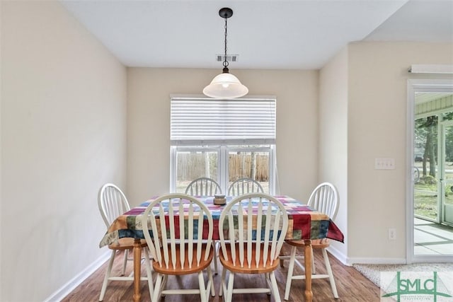 dining room featuring a wealth of natural light, visible vents, baseboards, and wood finished floors