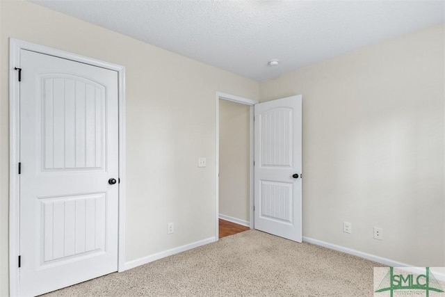 unfurnished bedroom featuring carpet, baseboards, and a textured ceiling