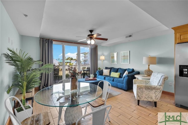 living area with visible vents, baseboards, ceiling fan, and light wood finished floors