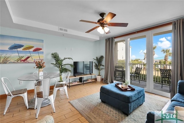 living area featuring a ceiling fan, light wood-style floors, and visible vents