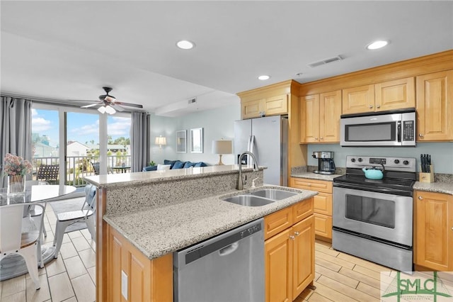 kitchen featuring visible vents, light brown cabinets, a center island with sink, stainless steel appliances, and a sink