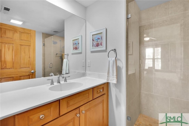 bathroom featuring vanity, a shower stall, and visible vents