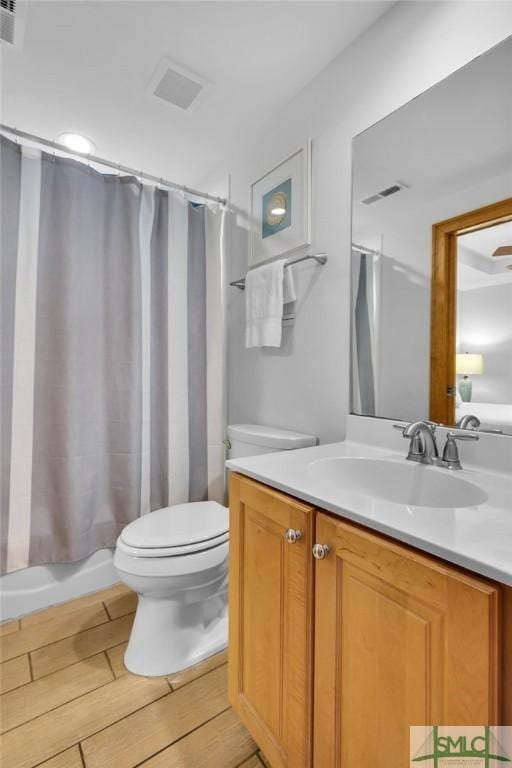 bathroom featuring visible vents, toilet, and vanity