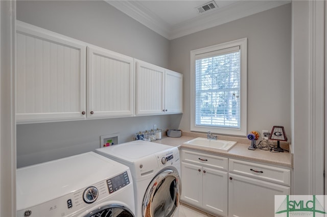 laundry area featuring visible vents, crown molding, washer and clothes dryer, cabinet space, and a sink