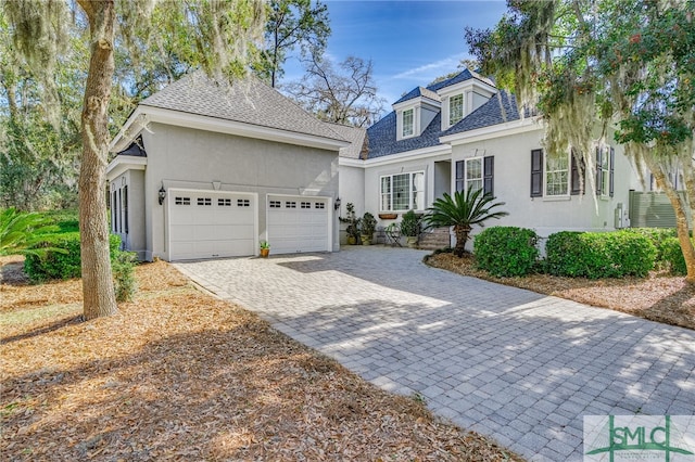 view of front of home featuring a garage, decorative driveway, a shingled roof, and stucco siding