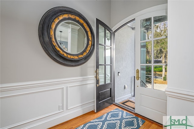 entrance foyer featuring a decorative wall, wood finished floors, and wainscoting