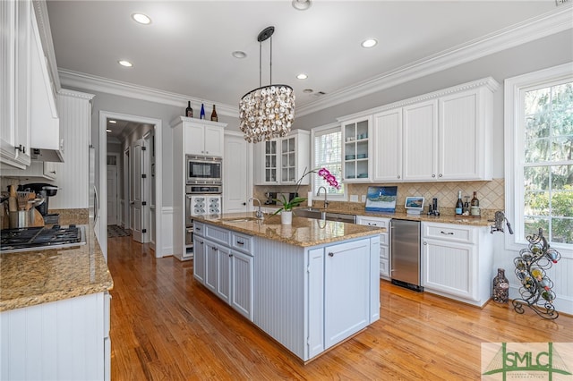 kitchen featuring appliances with stainless steel finishes, light wood-style flooring, white cabinets, and ornamental molding