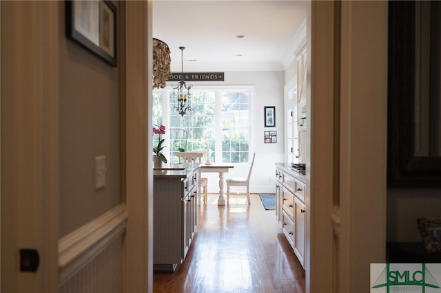 interior space with white cabinetry, crown molding, decorative light fixtures, and dark wood-type flooring