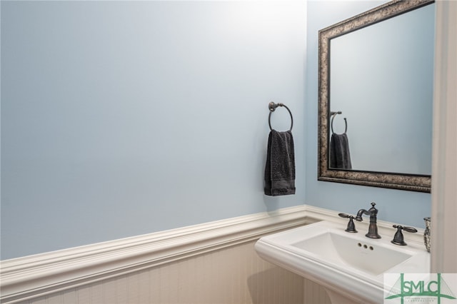 bathroom with a wainscoted wall and a sink