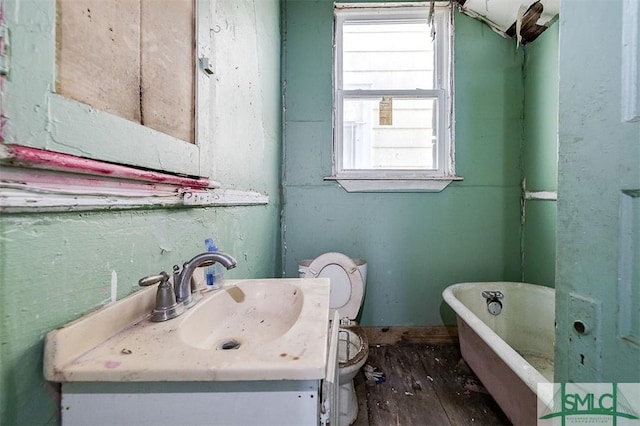 full bath with hardwood / wood-style flooring, toilet, vanity, and a freestanding tub