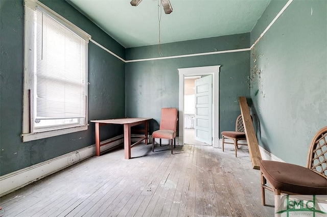 sitting room with wood-type flooring and a ceiling fan