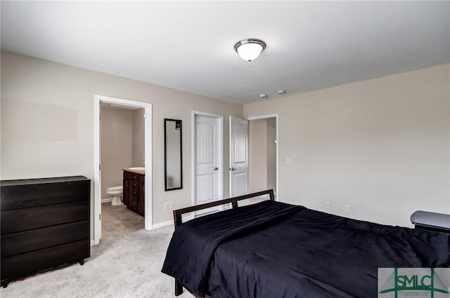 bedroom featuring baseboards, ensuite bathroom, and light carpet