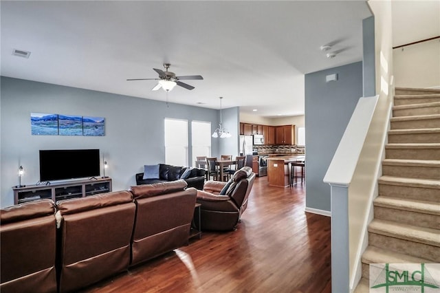 living room featuring stairway, visible vents, dark wood finished floors, and a ceiling fan