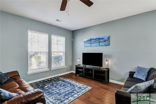 living area with a ceiling fan, wood finished floors, visible vents, and baseboards