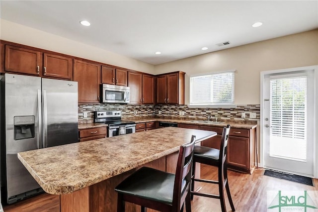 kitchen featuring visible vents, a kitchen breakfast bar, light wood-style floors, stainless steel appliances, and a sink