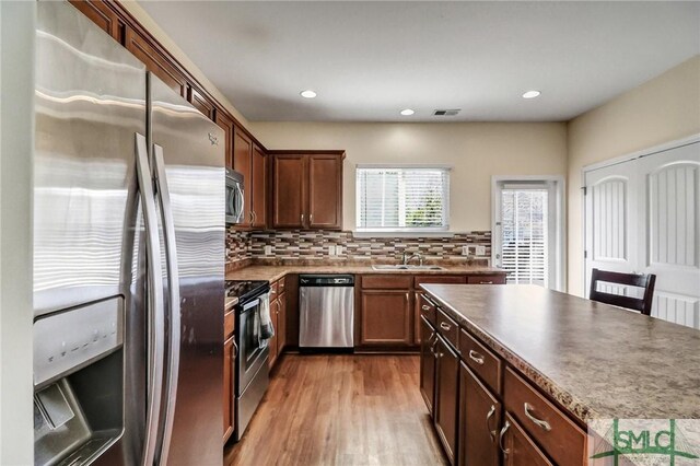 kitchen featuring visible vents, a sink, wood finished floors, stainless steel appliances, and decorative backsplash