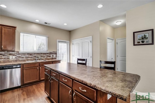 kitchen featuring visible vents, light wood finished floors, a sink, stainless steel dishwasher, and tasteful backsplash