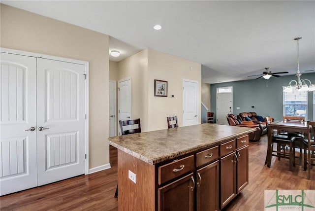 kitchen with dark wood-type flooring, decorative light fixtures, open floor plan, and a kitchen island