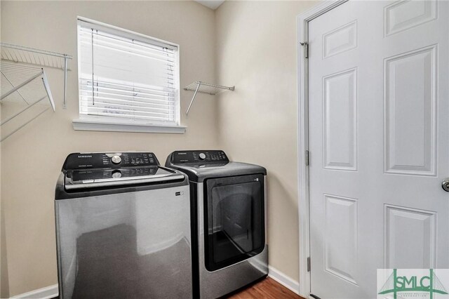 laundry room featuring washer and dryer, baseboards, wood finished floors, and laundry area