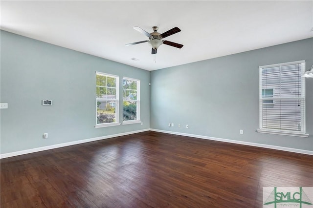 empty room with baseboards, dark wood-type flooring, and ceiling fan